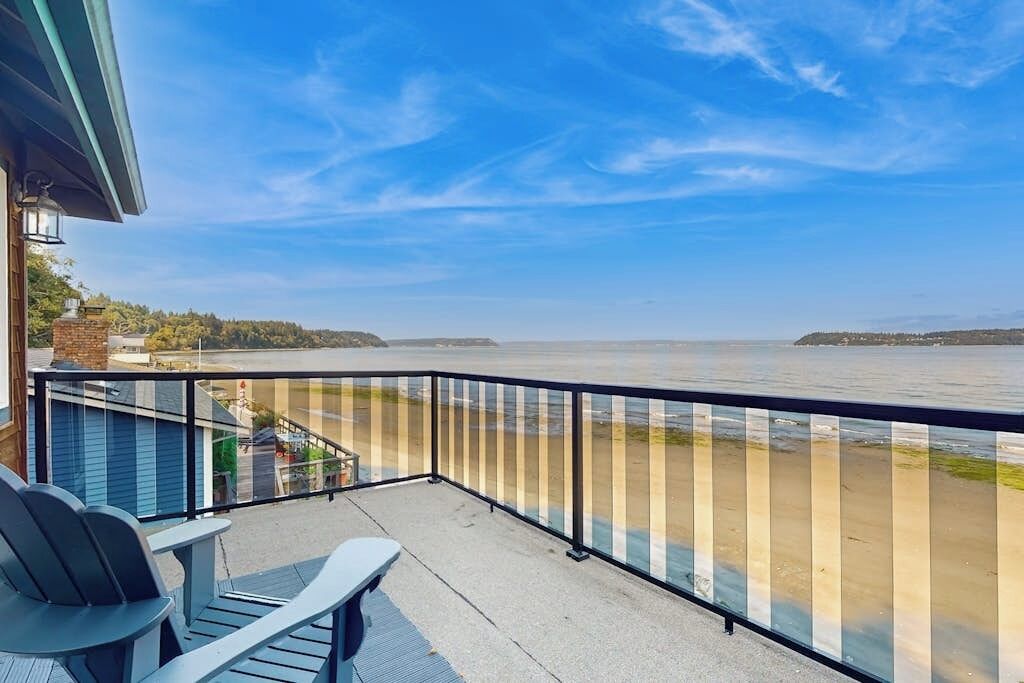 Un balcone con vista su un fiume, una sedia e un tavolo.