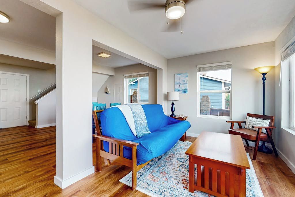A living room with a blue sofa, wooden coffee table, and a patterned rug.