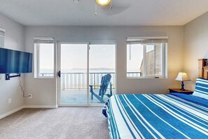 Ein Schlafzimmer mit einem Bett, einem Fernseher, einer Lampe und Blick ins Freie durch eine Schiebetür.