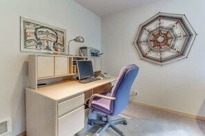Une pièce comprenant un bureau, une chaise, un ordinateur et des œuvres d’art accrochées aux murs.