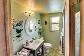Ein Badezimmer mit einem weißen Waschbecken, einer Toilette, einem Spiegel und einem Fenster.
