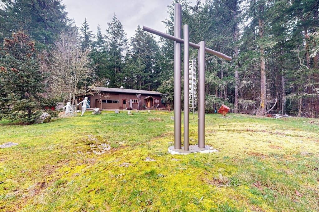 A rustic cabin with a metal sculpture in a forested area.