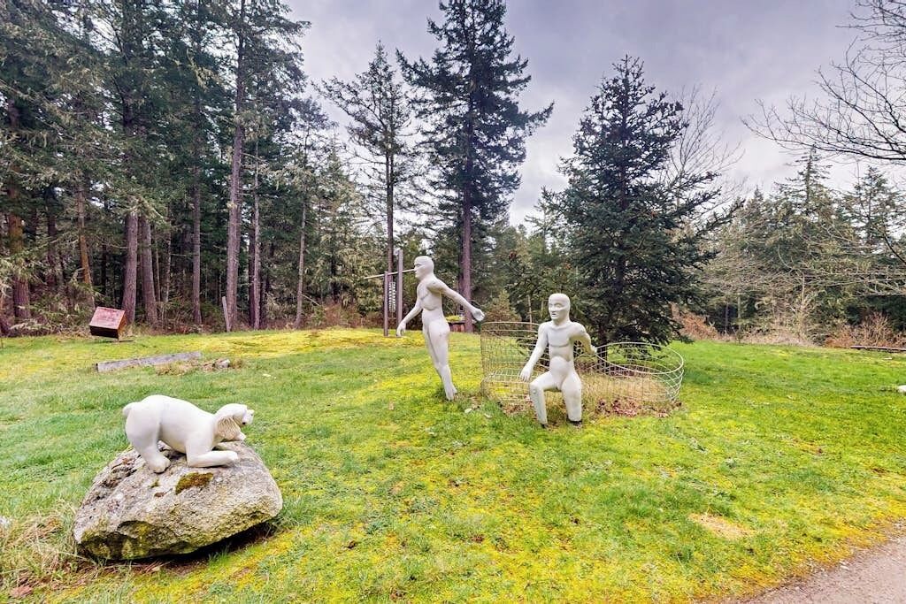 A sculpture garden with three figures and a bear on a rock.