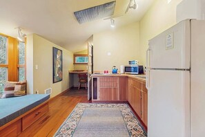 A compact kitchen with wooden cabinets, a refrigerator, and a microwave.
