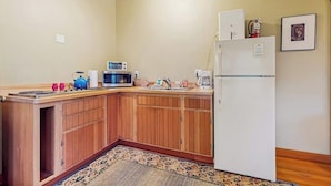 A compact kitchen with wooden cabinets, a microwave, a refrigerator, and a sink. - Dog Friendly Studio with Kitchenette, WiFi, Yard and Fire Pit near Eastsound Beach (Eastsound)