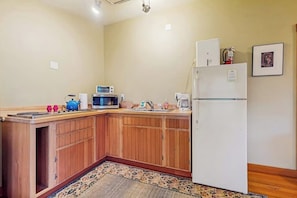 A compact kitchen with wooden cabinets, a microwave, a refrigerator, and a sink. - Dog Friendly Studio with Kitchenette, WiFi, Yard and Fire Pit near Eastsound Beach (Eastsound)