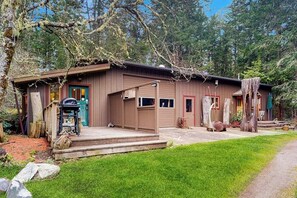 A rustic cabin with a porch, a grill, and a small deck.