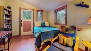 A bedroom with a bed, a chair, a desk, and a bookshelf. - Dog Friendly Studio with Kitchenette, WiFi, Yard and Fire Pit near Eastsound Beach (Eastsound)