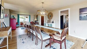 A dining area with a long wooden table, chairs, and a chandelier. - Spacious Dog Friendly 5 Bedroom Beachfront Home with Fenced Yard (Freeland)