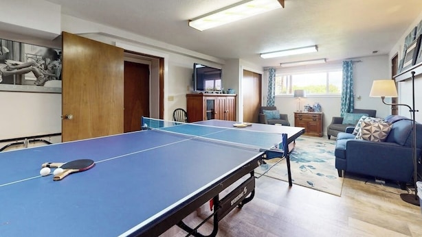 A room with a ping pong table, a sofa, a television, and a window with curtains. - Spacious Dog Friendly 5 Bedroom Beachfront Home with Fenced Yard (Freeland)