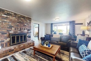 A living room with a brick fireplace, a leather sofa, and a coffee table.