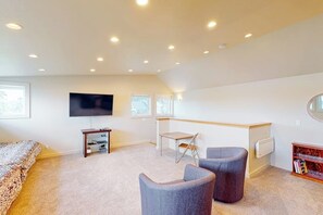 A bedroom with a bed, a TV, a desk, two chairs, and a bookshelf.