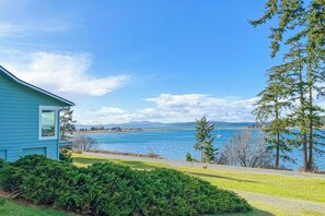 Une maison avec vue sur un lac et des montagnes au loin.