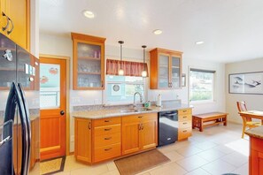 A kitchen with wooden cabinets, a black refrigerator, a sink, and a window with a view.