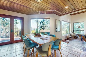 Une pièce spacieuse avec une grande table à manger, de nombreuses chaises et une vue sur l’extérieur grâce à de grandes fenêtres.