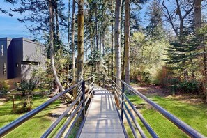 Un pont en bois menant à un bâtiment entouré de grands arbres.