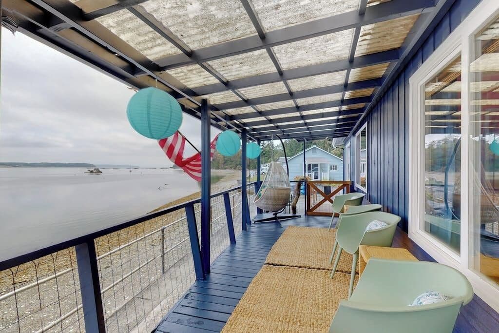 Zona relax esterna coperta con vista sulla spiaggia, una sedia a dondolo e un tavolo con sedie.