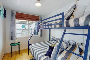 A bunk bed room with a window, curtains, and a small table.