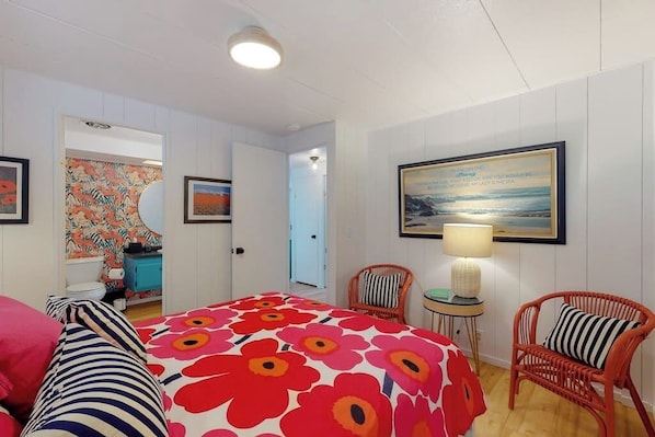 A hotel room with a bed, a chair, a table with a lamp, and a painting on the wall. - Stunning Soundfront Home in Coupeville with Private Beach Access and Fire Pit (Coupeville)