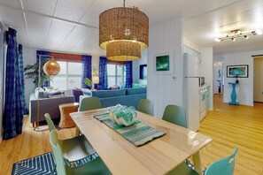 A modern interior with a dining area, a sofa, a television, and a kitchen area.