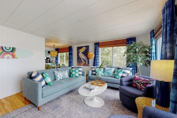 A modern living room with a blue sofa, a round coffee table, and a dark armchair.