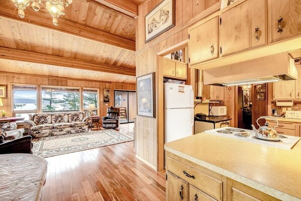A wooden cabin interior with a living area, kitchen, and dining space.