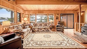 Ein Holzblockhaus-Interieur mit einem großen Teppich, einem Ledersofa und einem Kamin.