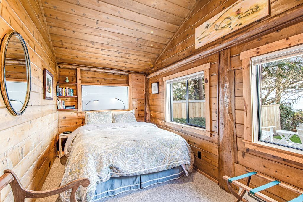 Een houten kamer met een bed, een raam en een spiegel.