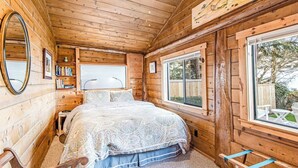 Una habitación de cabaña de madera con una cama, un ventanal y un espejo.