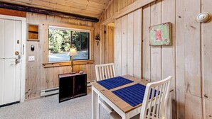 Un interior de madera con una mesa, sillas, una ventana y una puerta.