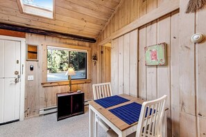 A wooden interior with a table and chairs, a window, and a door.