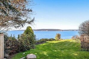 A grassy area with a view of a body of water and distant landforms.