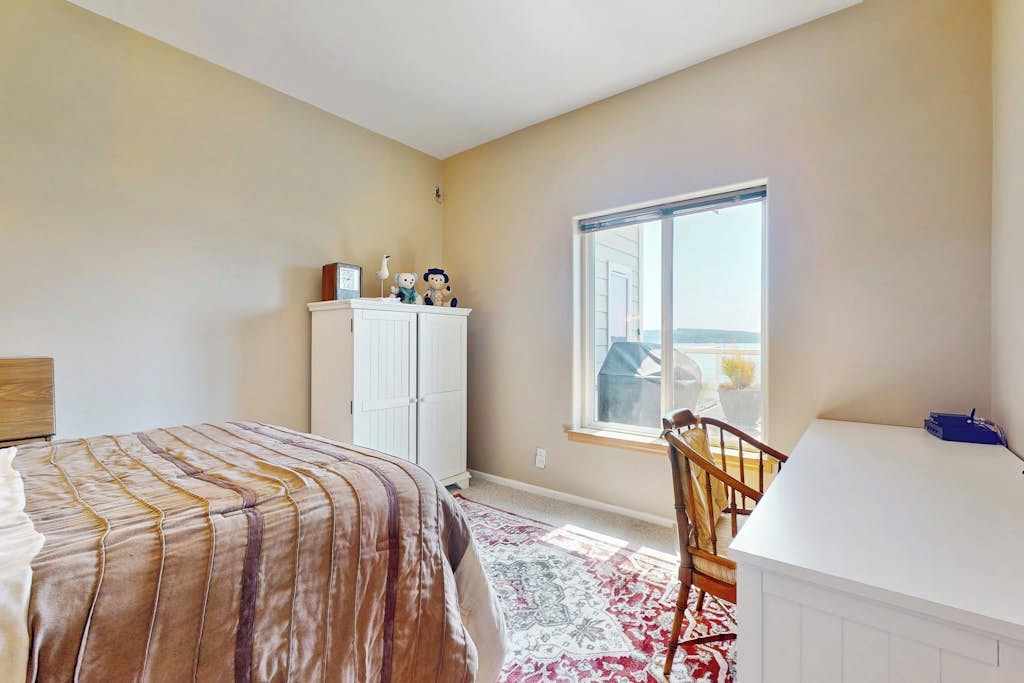 Un dormitorio con cama, escritorio, silla, armario y ventana con vistas.