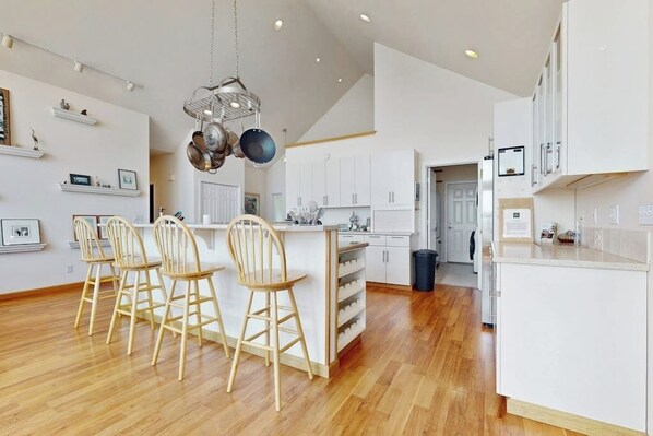Une cuisine moderne avec un îlot central, des chaises en bois et des meubles de rangement blancs.