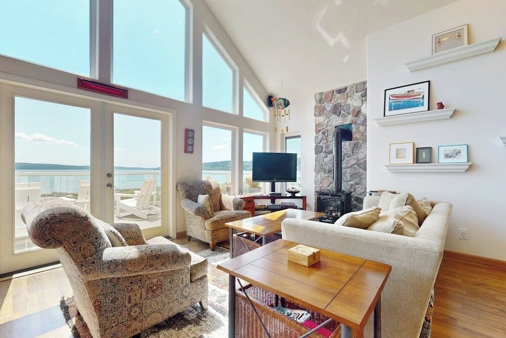 A spacious living room with a large window overlooking a scenic view, furnished with a sofa, armchairs, and a coffee table.