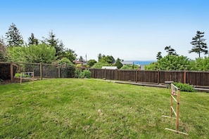 Ein Garten mit Holzzaun, Schaukel und Blick auf den Ozean.