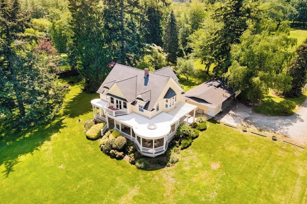 A large, two-story house with a wrap-around porch and a separate garage.