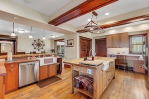 Une cuisine moderne avec des meubles en bois, des appareils électroménagers en acier inoxydable et des luminaires suspendus.