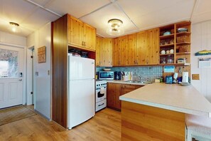 A kitchen with wooden cabinets, a white refrigerator, a microwave, and a sink. - Relaxing Beachfront Retreat with Panoramic Water Views and Spacious Outdoor Deck (Langley)