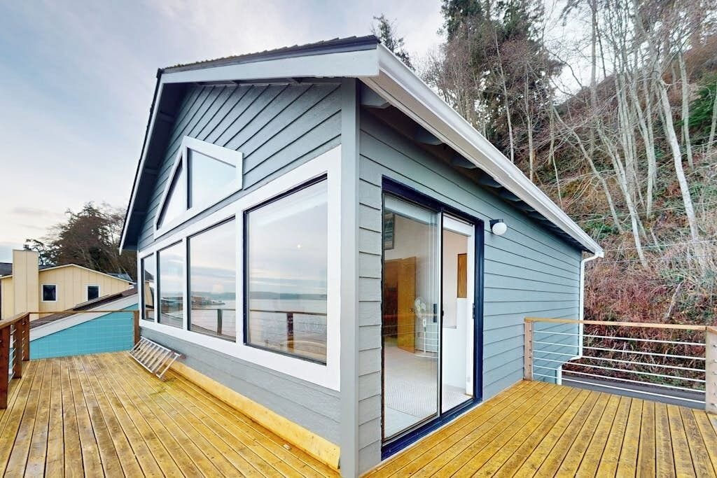 A modern house with a deck, large windows, and a view of the landscape.