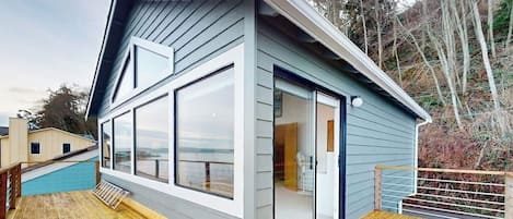 A modern house with a deck, large windows, and a view of the landscape.