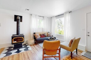 Een woonkamer met een open haard, een bank, twee fauteuils en een salontafel.