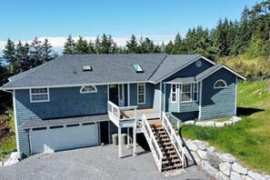 A two-story house with a garage, a front porch with a staircase, and a small deck. - Spacious Family Home with Game Room in Eastsound (Eastsound)