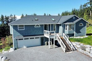 A two-story house with a garage, a covered porch, and a staircase leading to the upper level. - Spacious Family Home with Game Room in Eastsound (Eastsound)