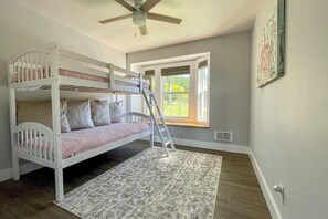 A bunk bed with a ladder, a ceiling fan, and a window with a view of greenery. - Spacious Family Home with Game Room in Eastsound (Eastsound)