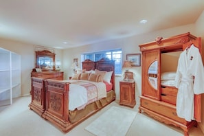 Un dormitorio con una cama grande, un armario de madera, un espejo y una mesita de noche.