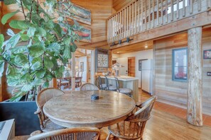A wooden interior with a round dining table, chairs, and a large plant.