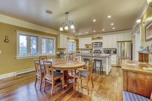 A spacious kitchen with wooden flooring, white cabinetry, and a central island. - Welcoming 5 Bedroom Orcas Island Home with Stunning Bay Views and Modern Amenities (Eastsound)