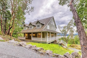 A two-story house with a porch, a covered front porch area, and a staircase leading to the main entrance. - Welcoming 5 Bedroom Orcas Island Home with Stunning Bay Views and Modern Amenities (Eastsound)
