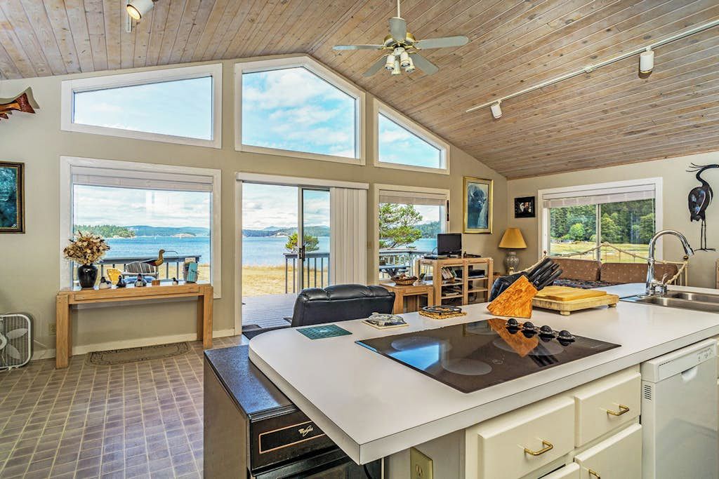 A spacious kitchen with a large island, multiple windows, and a view of the outdoors.